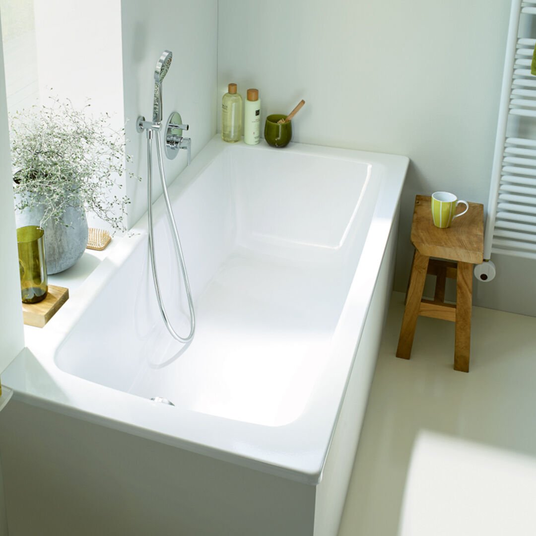 badewanne in ecke mit verchromter armatur und holzhocker