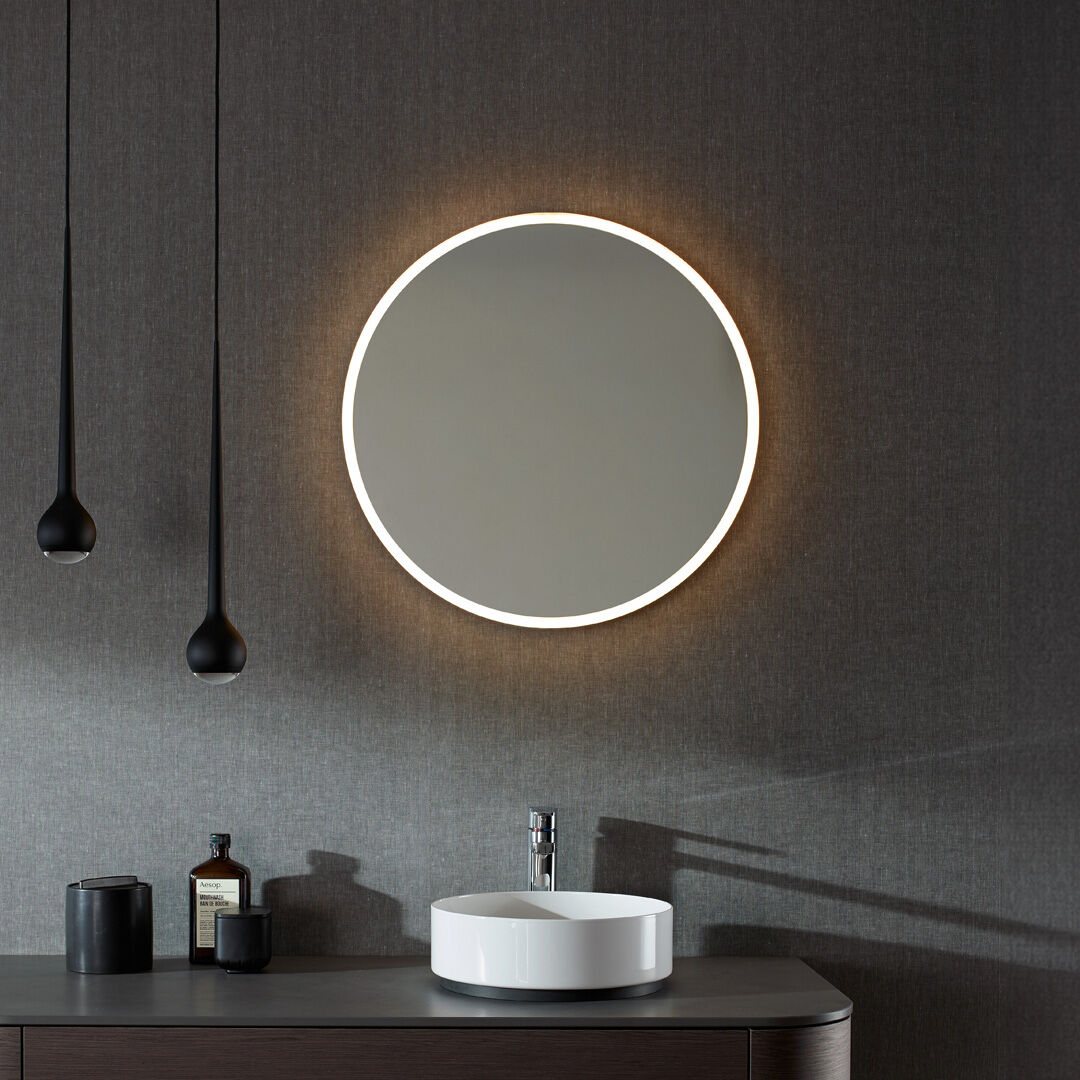 runder lichtspiegel &uuml;ber waschtisch mit rundem lavabo in dunklem badezimmer