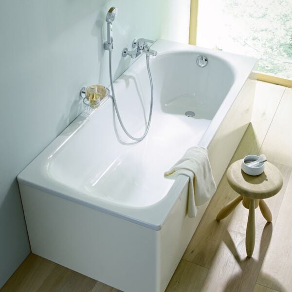 kleine badewanne an wand mit duscharmatur und holzhocker nebenan