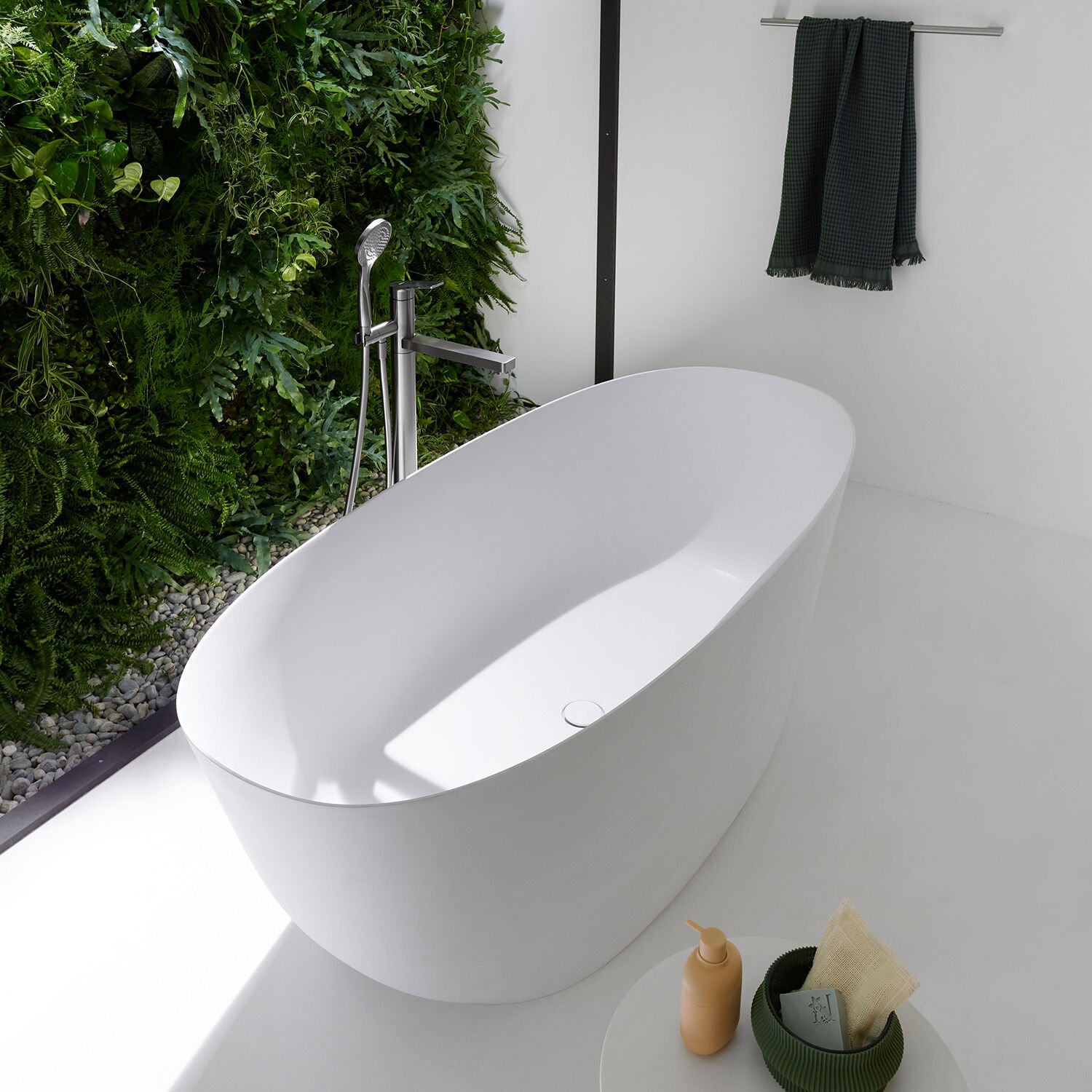 freistehende ovale badewanne neben grossem fenster vor garten