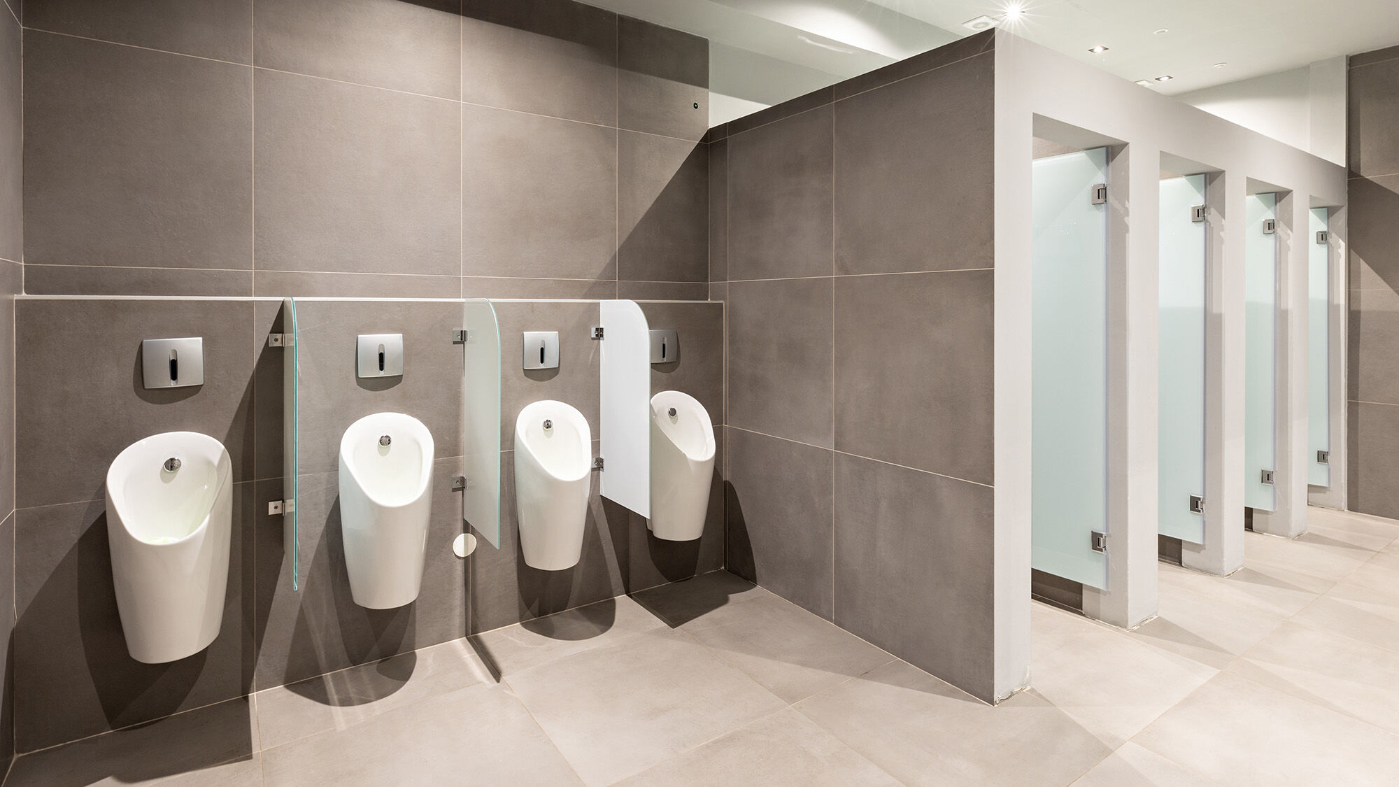 bagno pubblico con orinatoi e pareti grigie