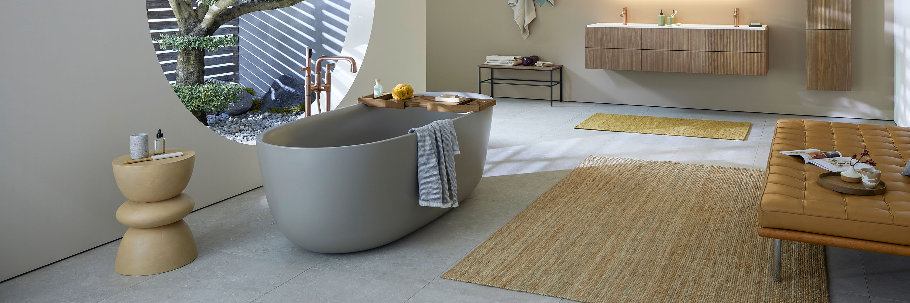 graue freistehender badewanne vor rattan teppich und modernen holz badm&ouml;beln