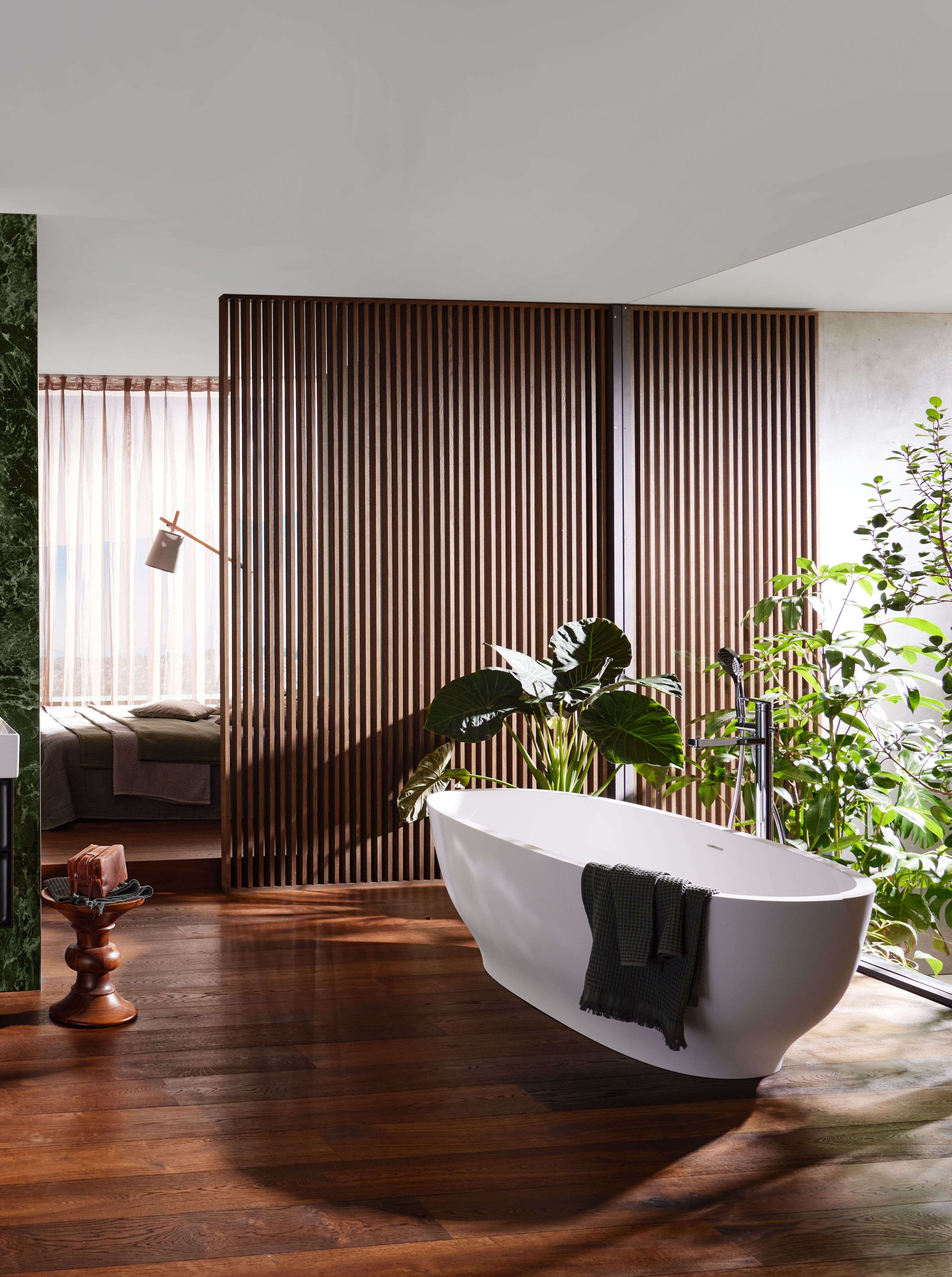 Le bon choix de matériaux pour votre salle de bains individuelle marbre et surfaces en bois dans une salle de bain luxueuse avec miroir rond et baignoire sur pied