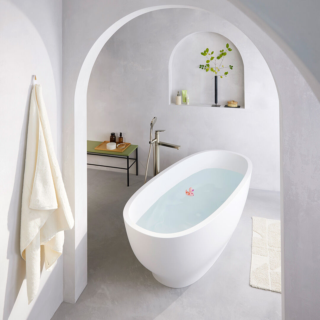 freistehende ovale badewanne neben grossem fenster vor garten